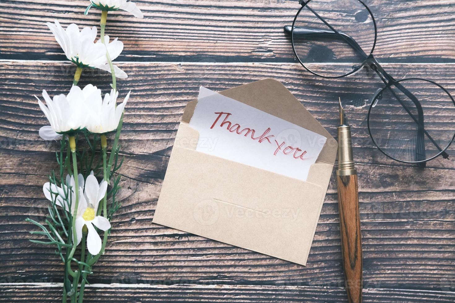 messaggio di ringraziamento e busta sul tavolo di legno foto