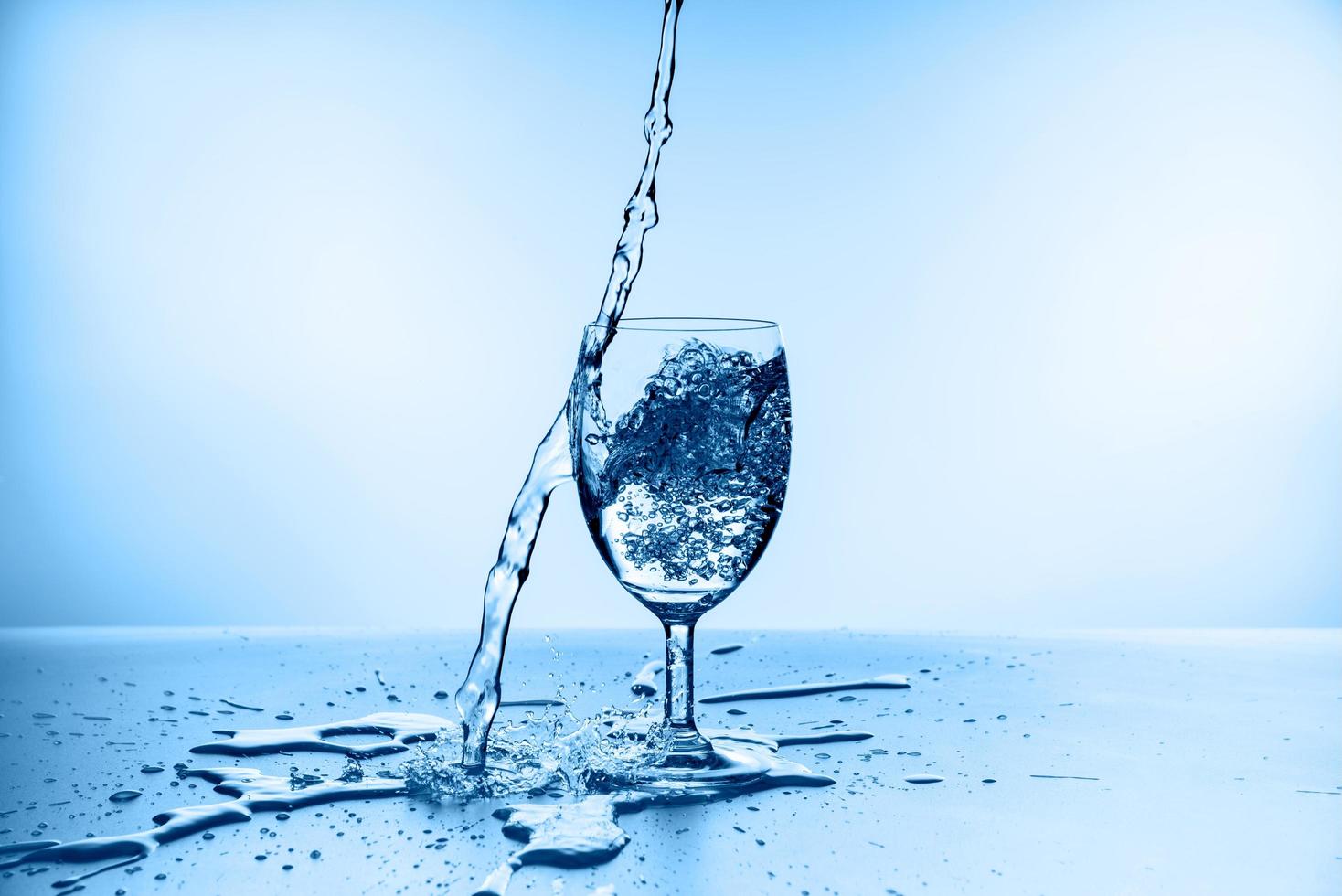 spruzzi d'acqua dal vetro isolato su sfondo blu foto