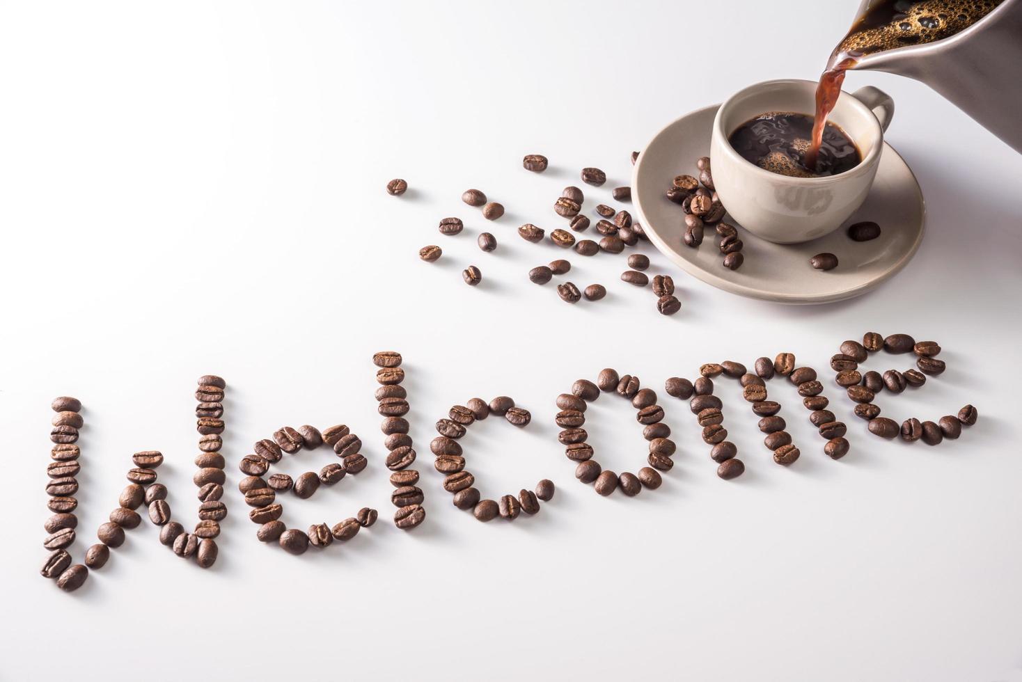 tazza di caffè e testo fatto di chicchi di caffè, isolati su bianco. testo la parola benvenuto fatta di chicchi di caffè. font foto