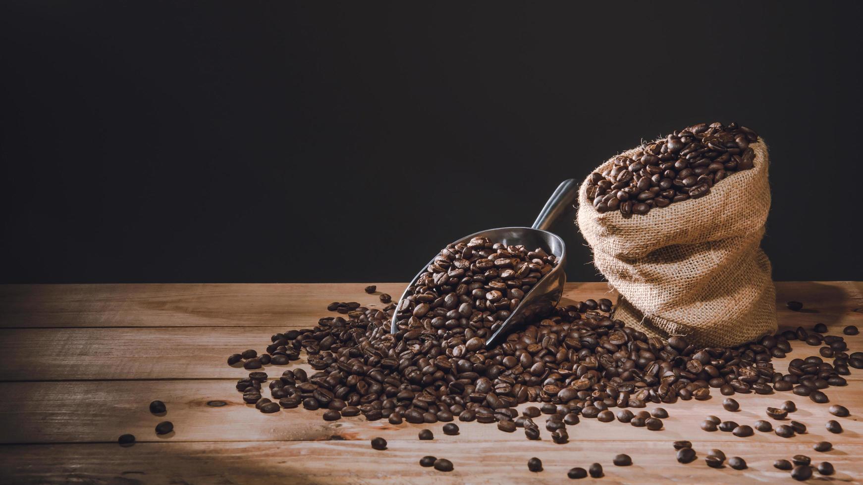 tazza di caffè e chicchi di caffè sparsi sul tavolo in legno vecchio con copie per il tuo testo foto