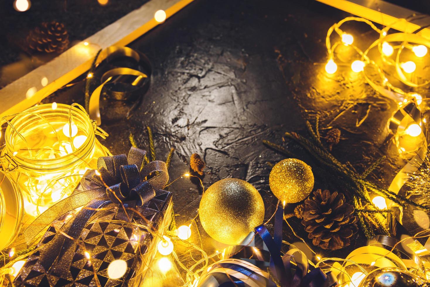 regalo di natale con nastro azzurro e palle di decorazione natalizia su sfondo nero bokeh astratto con spazio copia e luci a led decorative. buon natale e anno nuovo. foto