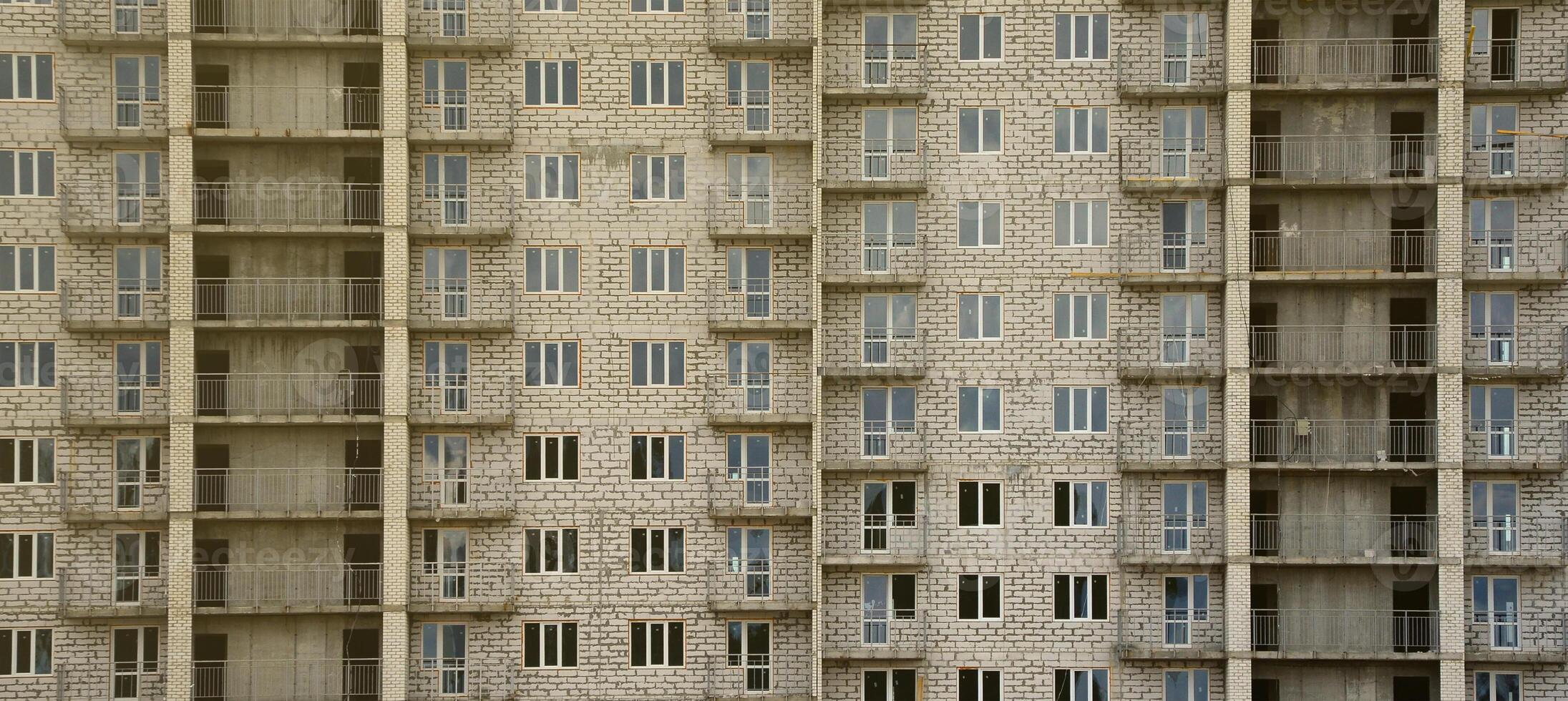 strutturato modello di un' russo pietra bianca Residenziale Casa edificio parete con molti finestre e balcone sotto costruzione foto