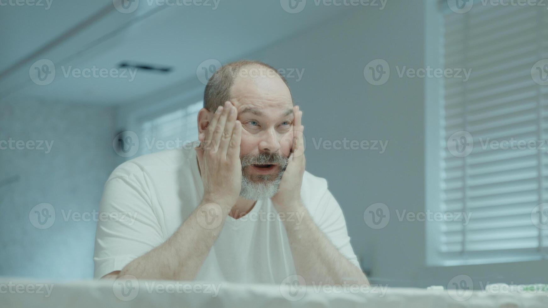 uomo che lava e asciuga il viso in bagno foto