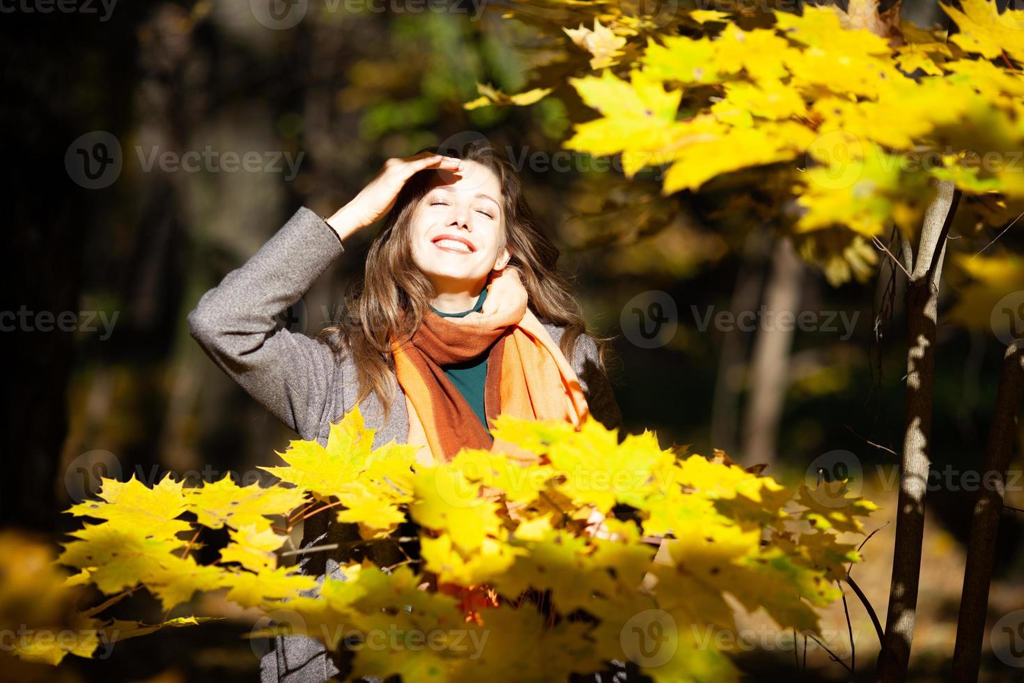 felice giovane donna al sole tra il giallo fogliame autunnale foto