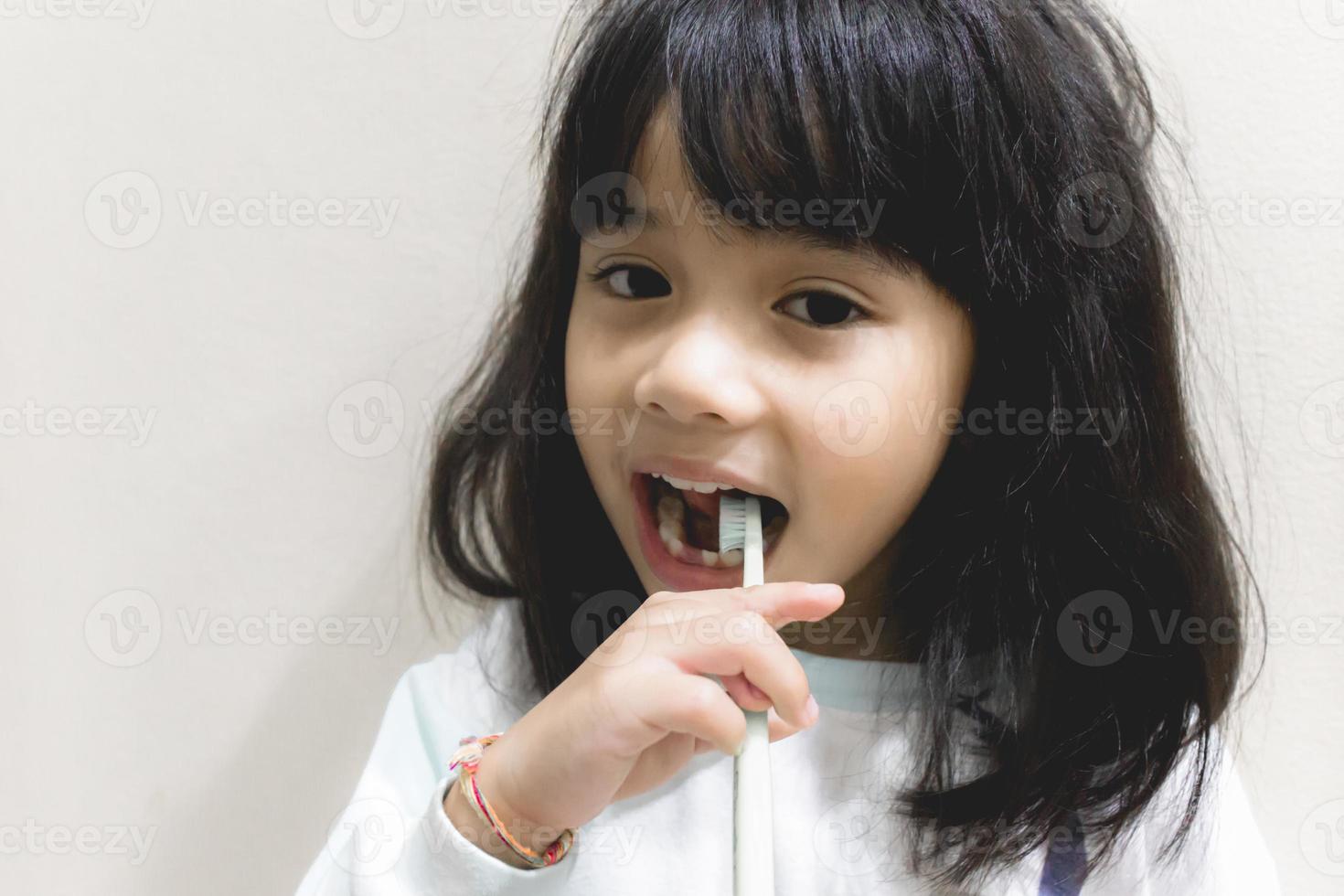 ragazza che si lava i denti con lo spazzolino da denti foto