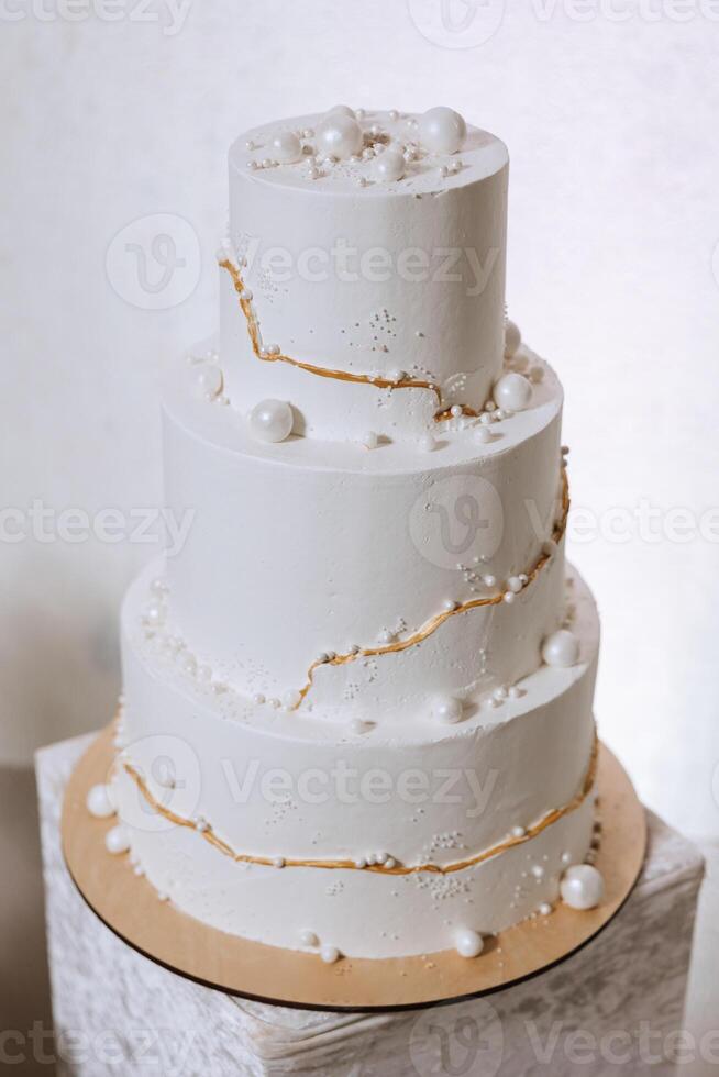 un' grande lussuoso multilivello nozze torta è decorato con bianca perle nel il banchetto sala. nozze dolce sotto il sera luce. nozze arredamento. foto