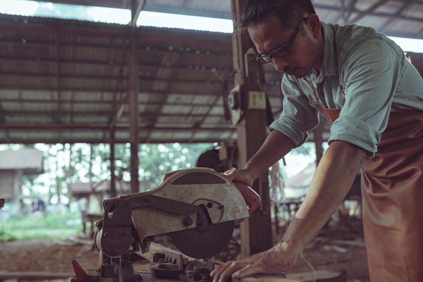 falegname sta tagliando il legno con una motosega per lavorare sulla sua falegnameria. foto