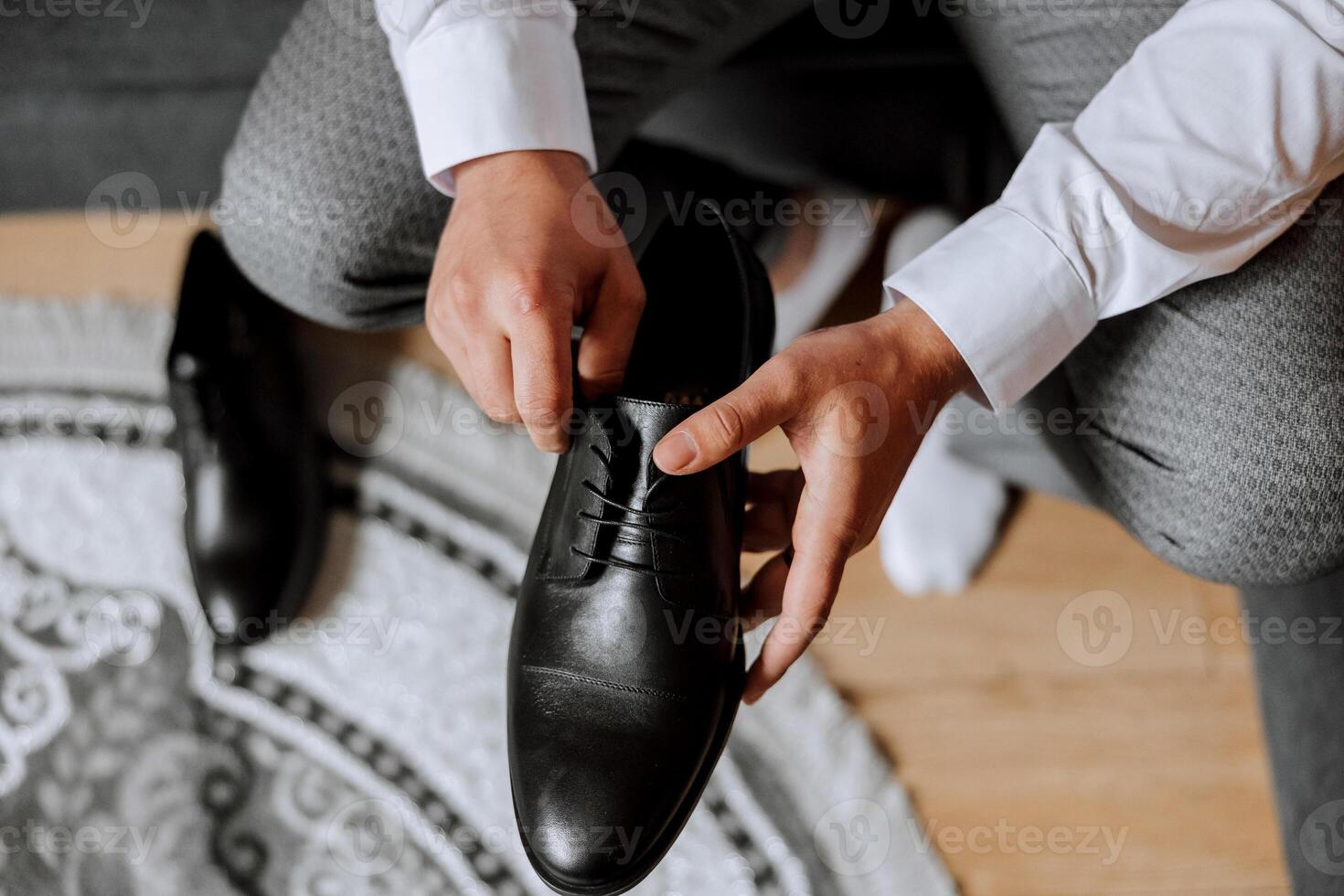 un elegante uomo indossa nero pelle formale scarpe. legatura scarpe. attività commerciale uomo legatura lacci delle scarpe su il pavimento. su vicino il sposo è preparazione per il nozze. foto