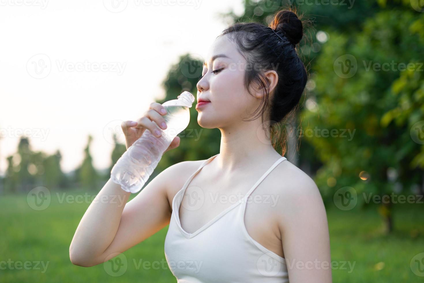 immagine di una donna asiatica che fa yoga all'aperto, beve acqua foto