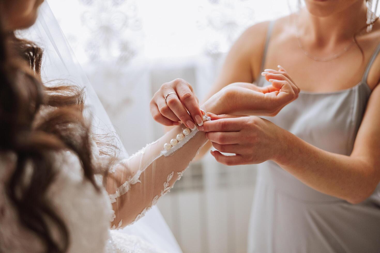 mattina di il sposa. il della sposa domestica di onore aiuta il sposa pizzo su sua vestire, allacciare pulsanti su il vestito o maniche. amiche Aiuto il sposa allacciare sua vestito foto