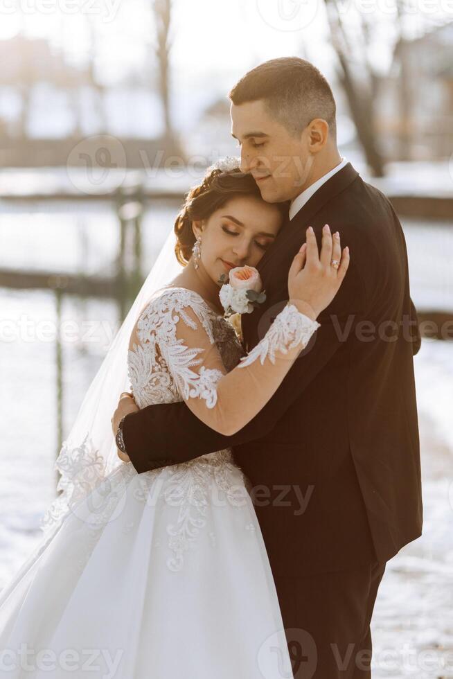 inverno nozze. un' contento coppia nel nozze Abiti siamo abbracciare e sorridente nel un' inverno parco coperto con neve su loro nozze giorno. inverno amore storia di un' bellissimo coppia nel nevoso inverno tempo metereologico foto