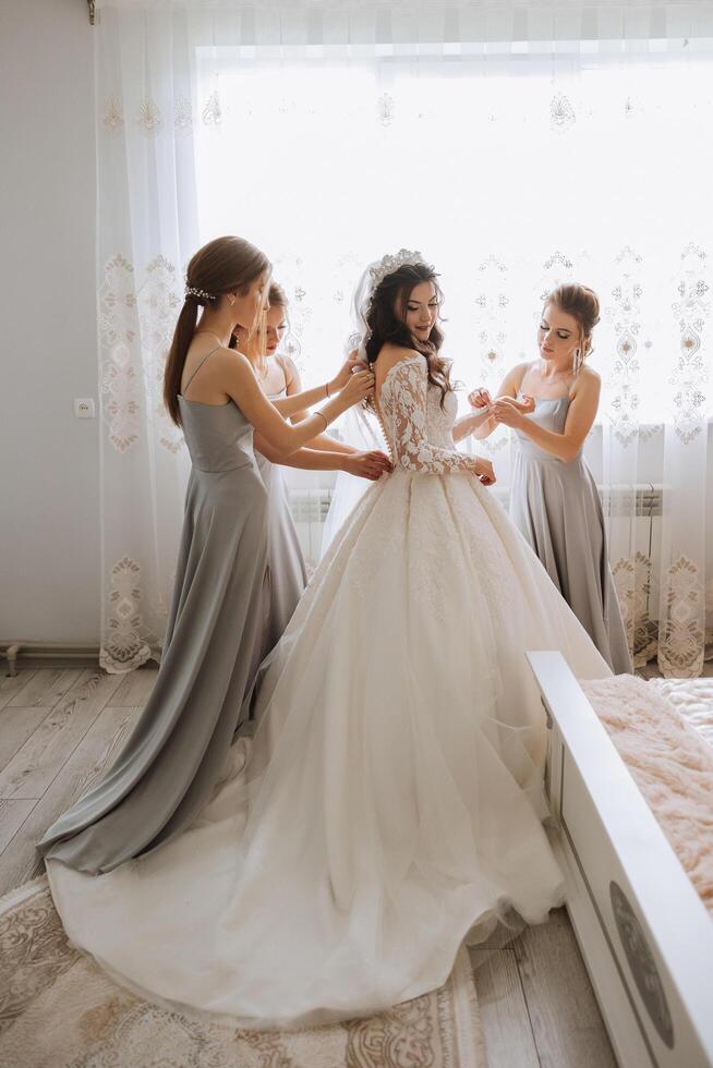 amici rallegrarsi con il sposa nel il mattina. essi prendere immagini, Sorridi, Aiuto il sposa allacciare sua vestire. foto