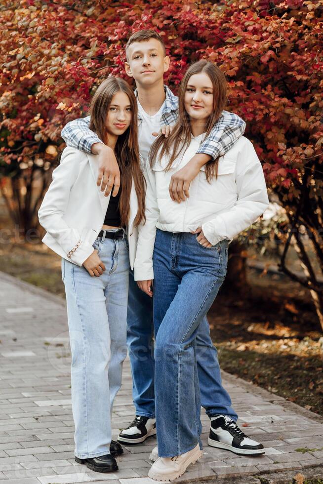 tre adolescenti di diverso sessi, in posa nel natura. adolescenziale compagne di classe siamo riposo contro il sfondo di un autunno foresta. foto