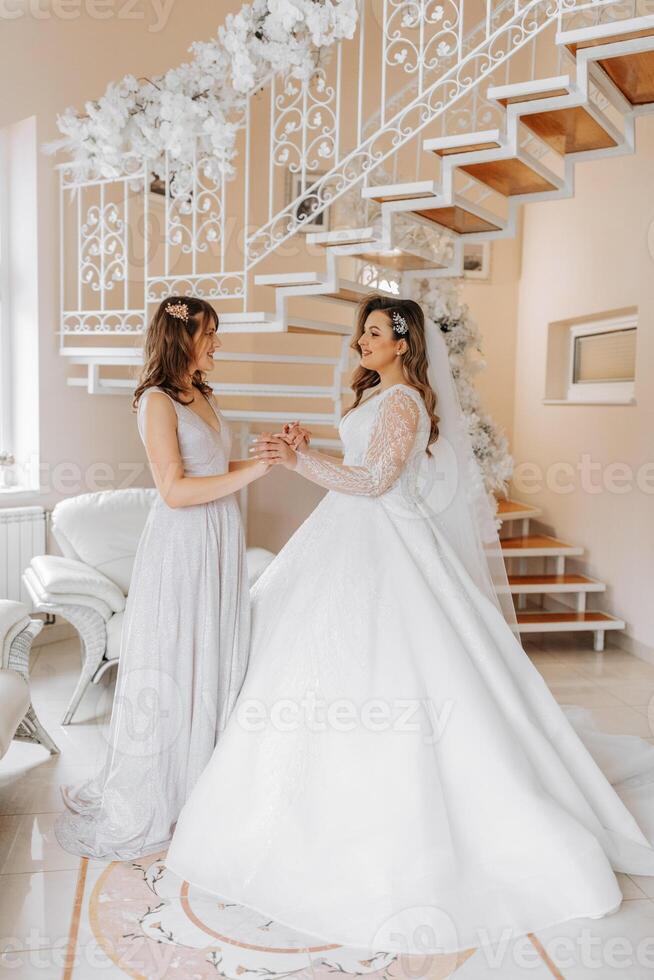 un' amico aiuta il sposa allacciare sua vestire. un' donna aiuta sua amico allacciare il pulsanti su il indietro di sua nozze vestire. il mattina di il sposa, il creazione di un' famiglia, un importante evento. foto