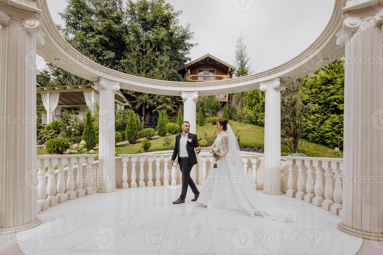 un' camminare di bellissimo e sorridente spose su loro nozze giorno nel un' meraviglioso posto. contro il sfondo di alto colonne nel il romano stile. foto