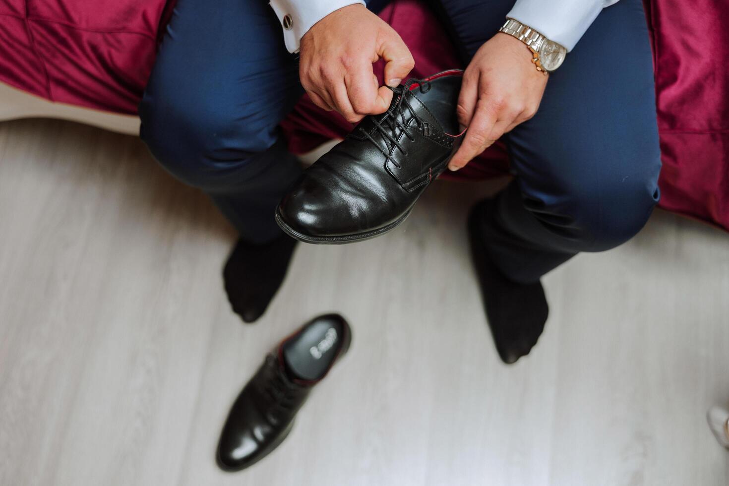 un elegante uomo indossa nero pelle formale scarpe. legatura scarpe. attività commerciale uomo legatura lacci delle scarpe su il pavimento. su vicino il sposo è preparazione per il nozze. foto