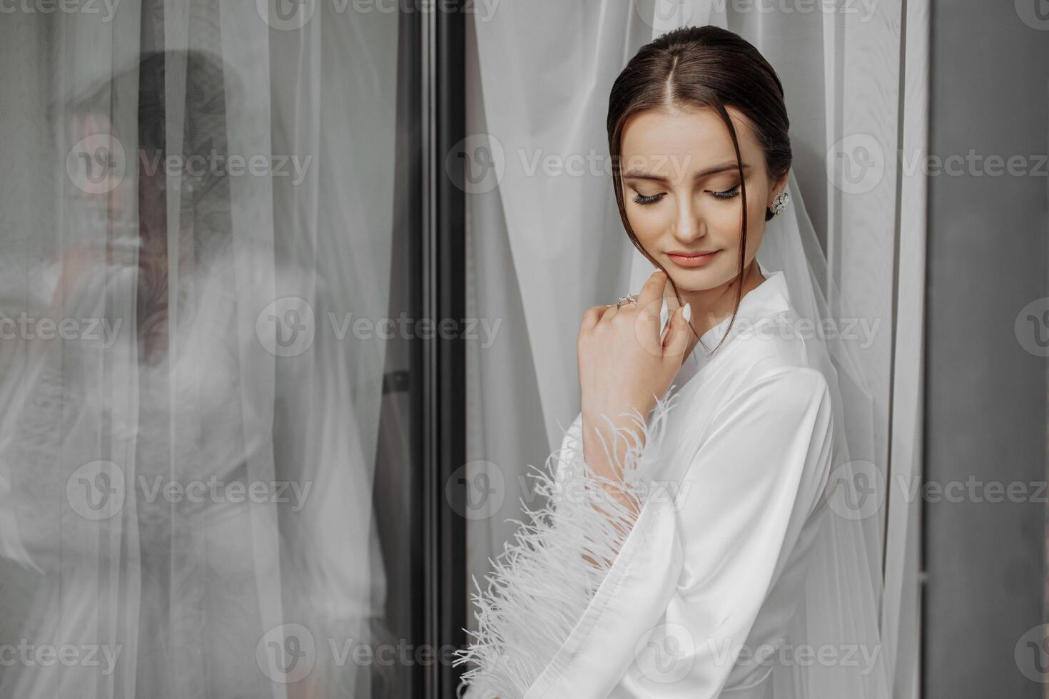 ritratto di sposa ragazza nel bianca toga con professionale acconciatura e naturale trucco nel Hotel camera con riflessione nel finestra. il migliore giorno foto