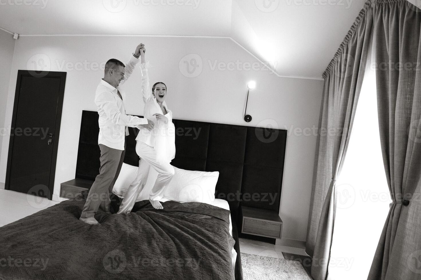 il mattina di il sposa e sposo nel un' Hotel camera. contento e nel amore sposa e sposo salto e avendo divertimento su il letto. fiducioso ragazza-sposa e bello sposo. preparazione per il nozze foto