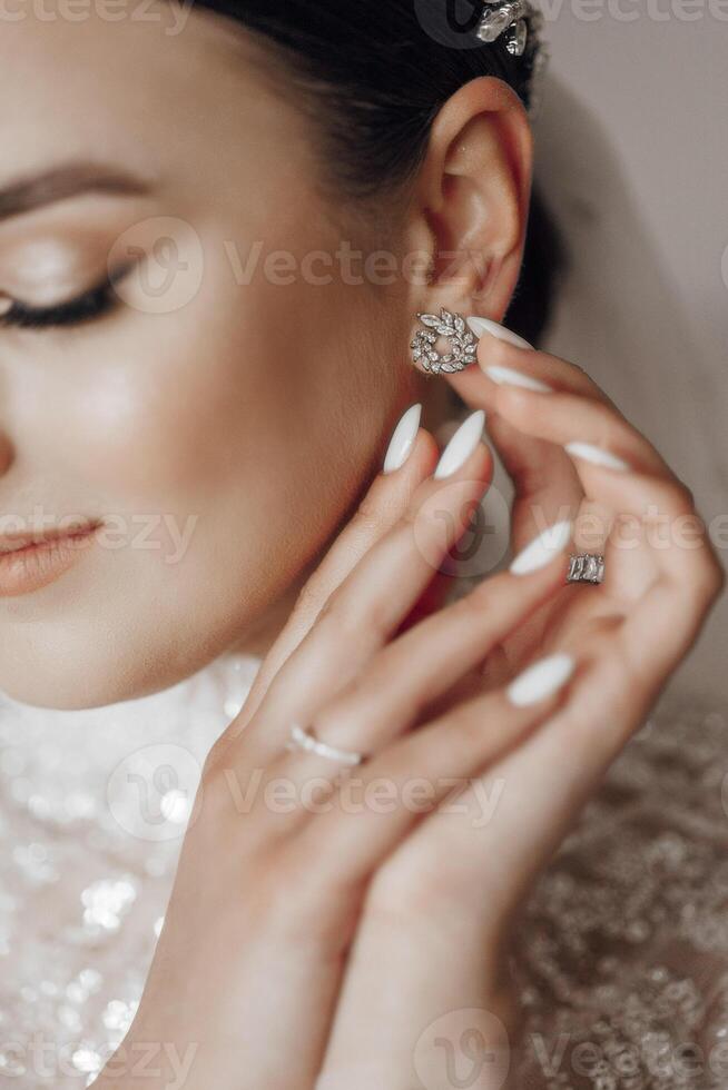 il sposa indossa un orecchino. nozze ritratto di il sposa. bellissimo manicure e acconciatura foto