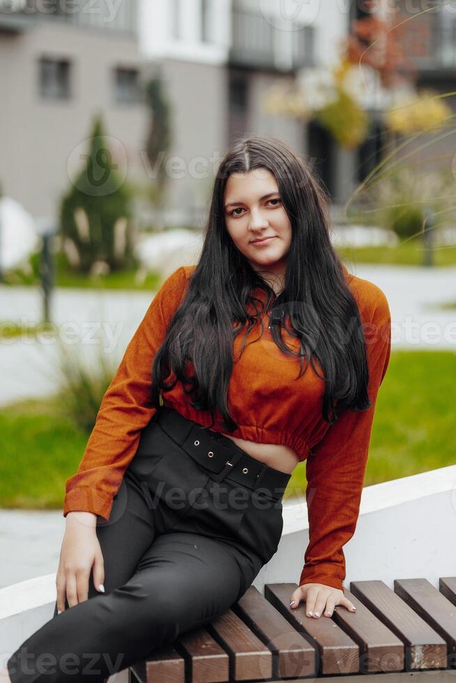 verticale foto. bellissimo spensierato giovane adolescenziale ragazza nel casuale Abiti. ritratto di un' bellissimo ragazza contro il sfondo di natura con un' sfocato sfondo. foto