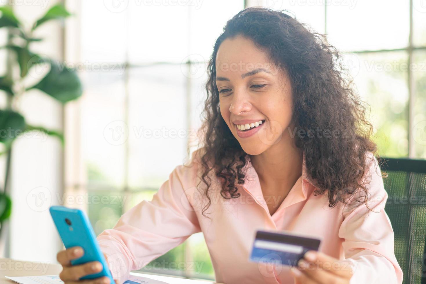 bella donna latina che utilizza smartphone con carta di credito foto