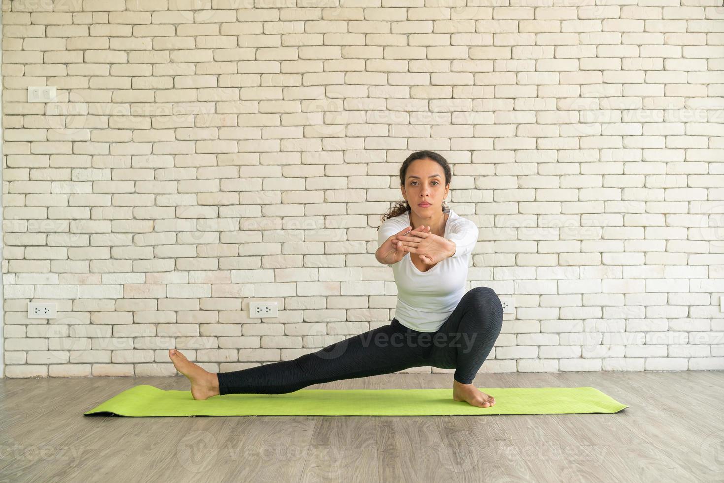 donna latina che pratica yoga su mat foto