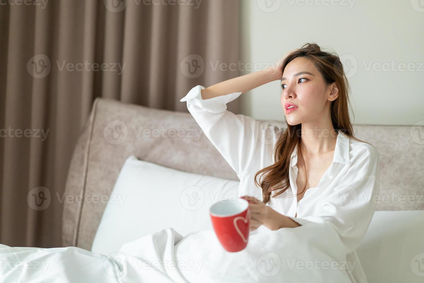 ritratto bella donna sveglia e tenendo tazza di caffè o tazza sul letto foto