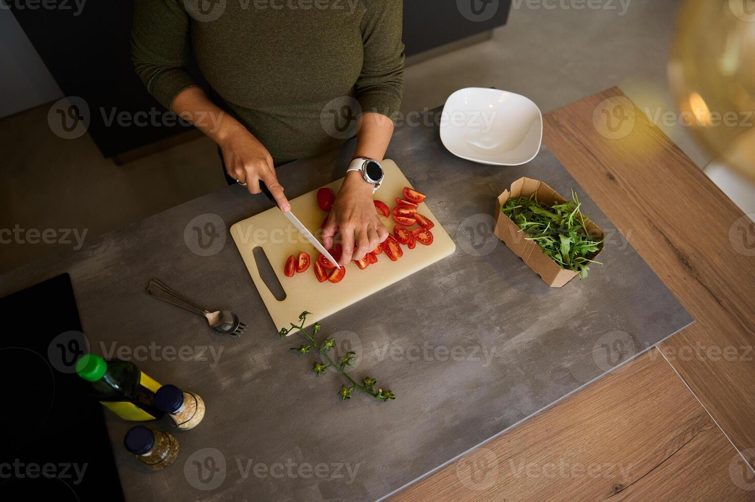 direttamente sopra mani di un' femmina capocuoco taglio pomodori mentre fabbricazione fresco salutare insalata, in piedi a cucina contatore foto