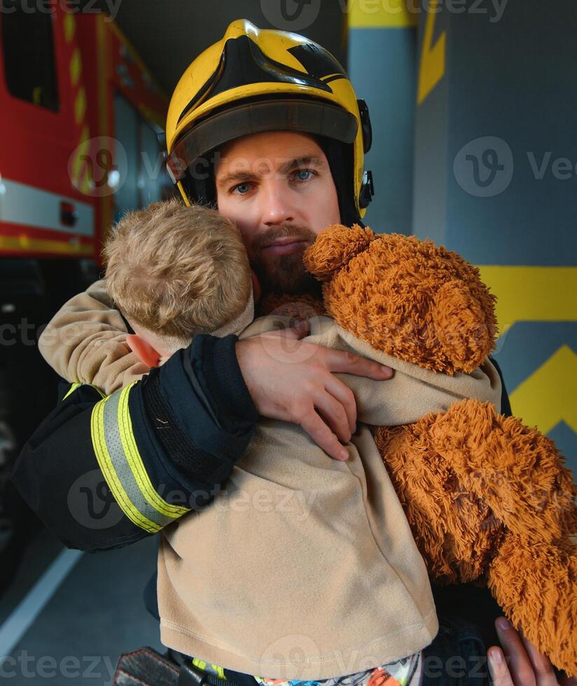 pompiere Tenere bambino ragazzo per Salva lui nel fuoco e fumo, vigili del fuoco salvare il ragazzi a partire dal fuoco foto