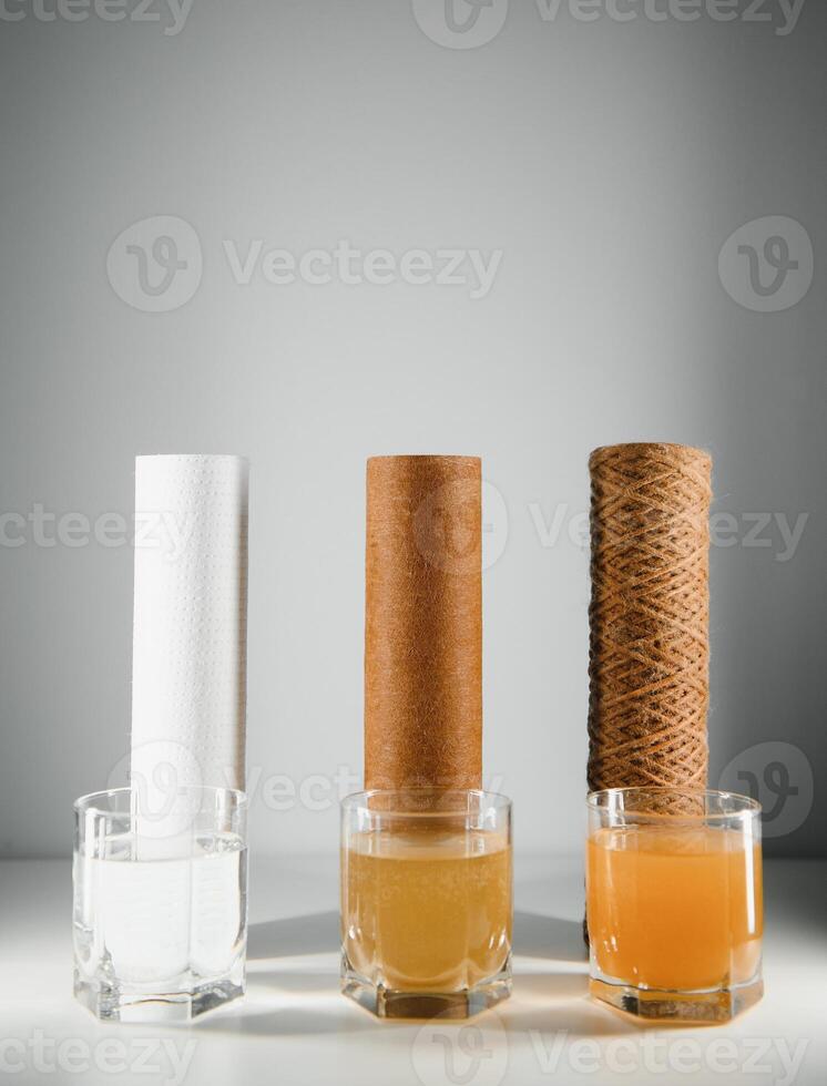 acqua filtri concetto. carbonio cartucce e un' tre bicchieri su un' bianca sfondo. domestico filtrazione sistema. foto
