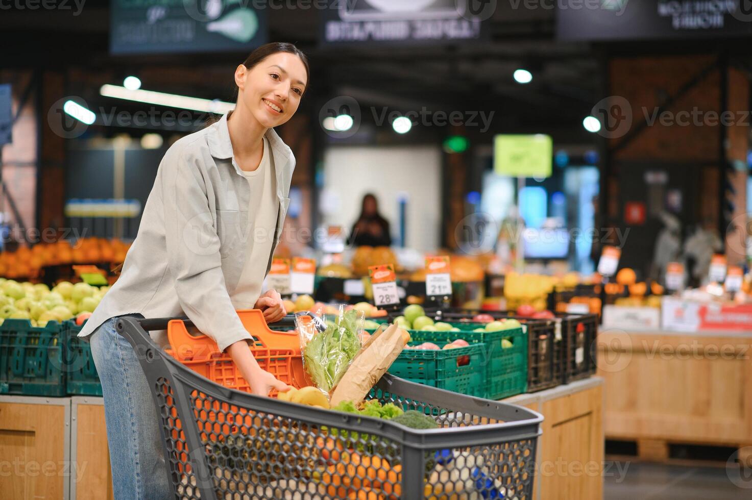 giovane donna acquisto verdure a drogheria mercato foto