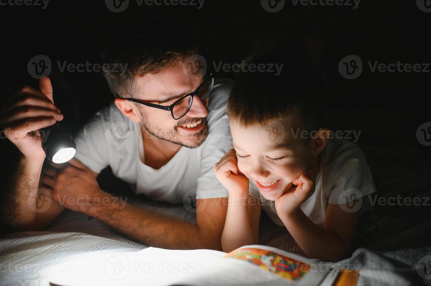 contento famiglia lettura di andare a dormire storia sotto coperta nel sera. padre e figlio trascorrere tempo insieme. Il padre di giorno foto