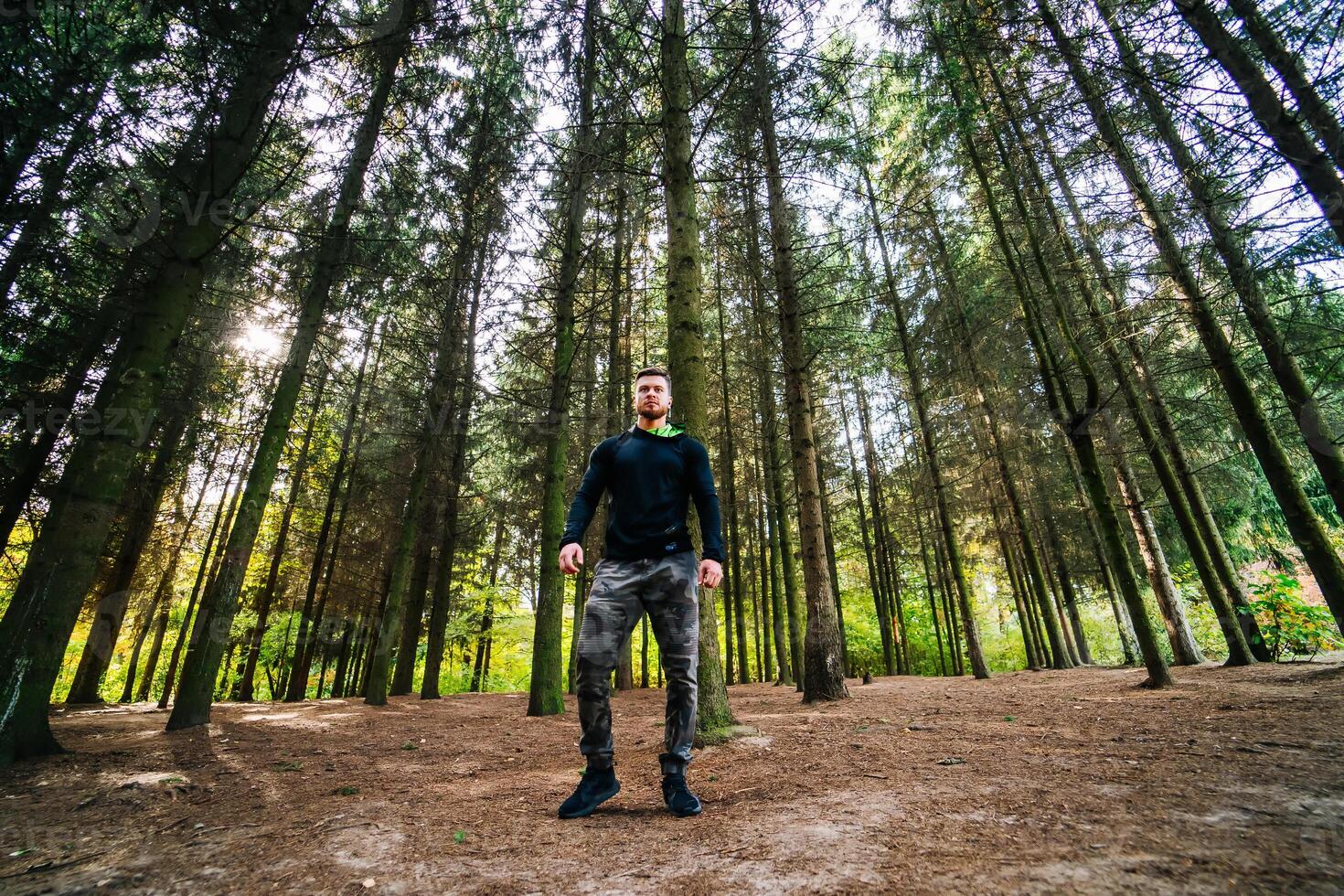 uomo in piedi maestosamente nel il cuore di natura. un' uomo in piedi nel il mezzo di un' foresta foto