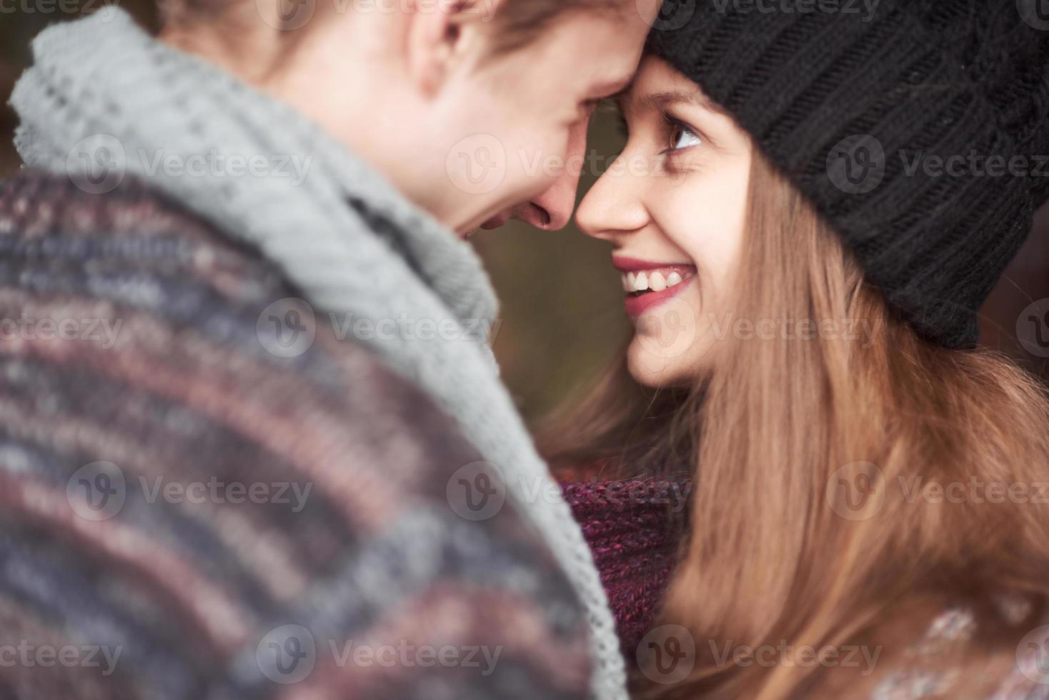 mezzo busto ritratto di giovane uomo spensierato e donna che si abbracciano e sorridono. sono in piedi nella foresta invernale e guardano la telecamera con felicità foto