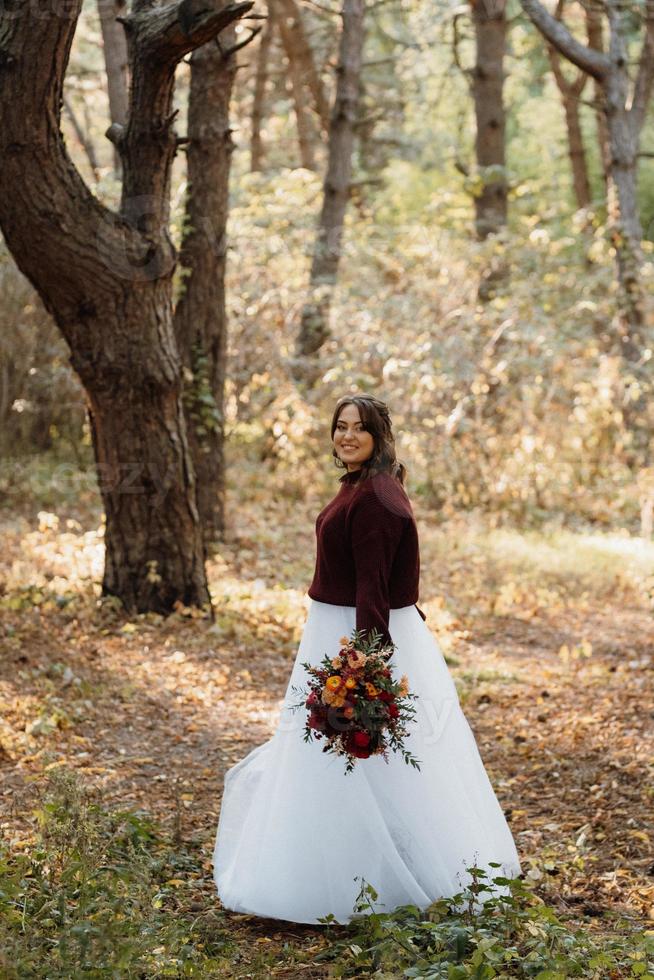 ragazza in abito da sposa nella foresta autunnale foto