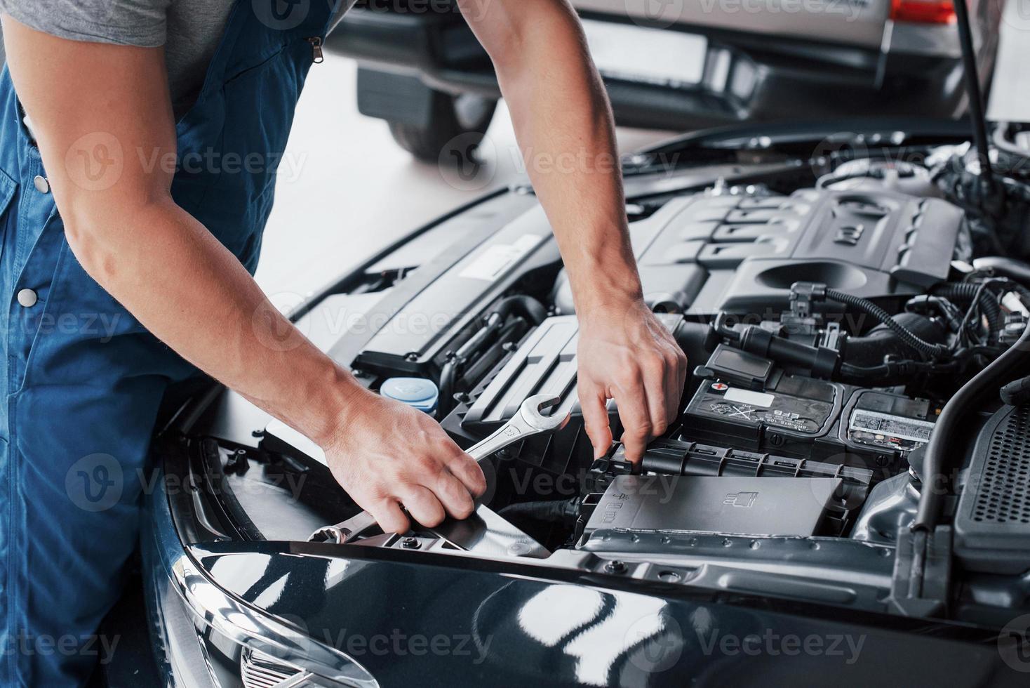 le mani del meccanico controllano la funzionalità dell'auto nel cofano aperto, primo piano. foto