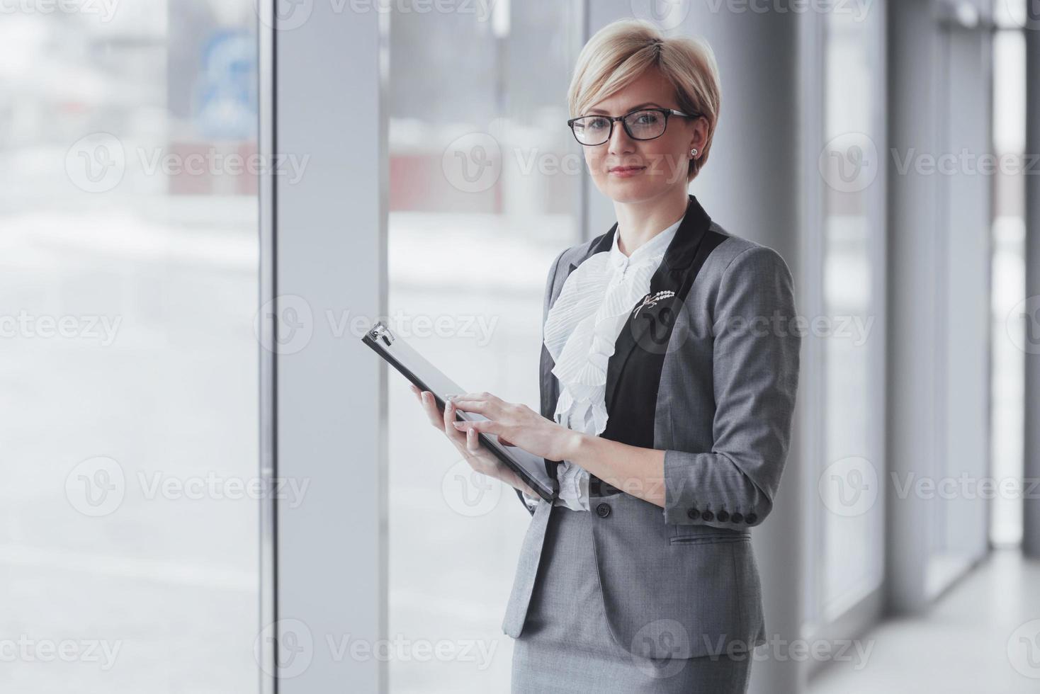 donna d'affari sorridente fiduciosa che guarda l'obbiettivo in ufficio foto