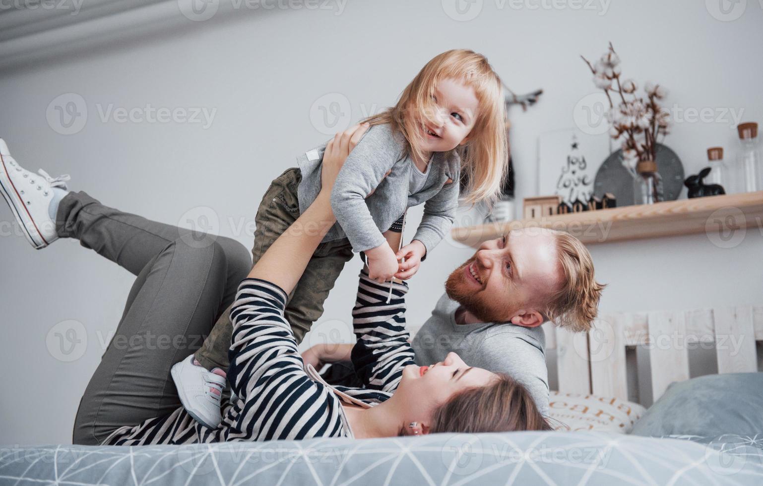 famiglia felice insieme. madre, padre e figlia che si abbracciano in camera da letto in un giorno festivo foto