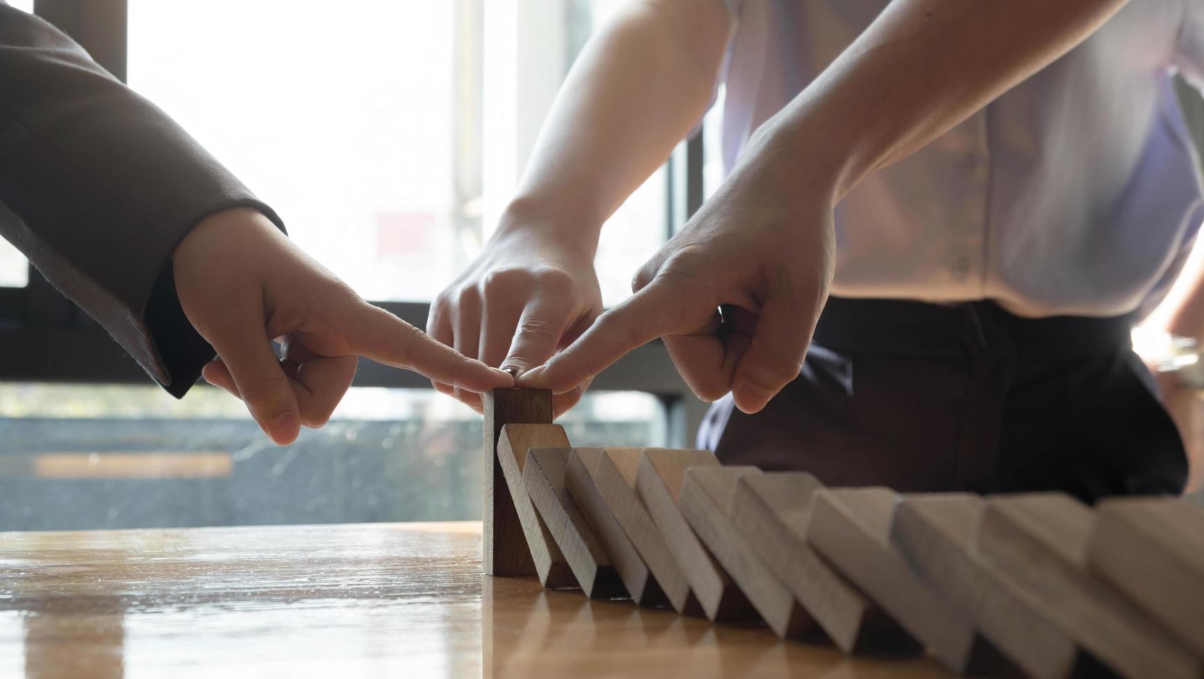 primo piano squadra uomo d'affari mano che smette di cadere effetto domino in legno da continuo rovesciato o rischio, strategia e concetto di intervento di successo per le imprese. foto