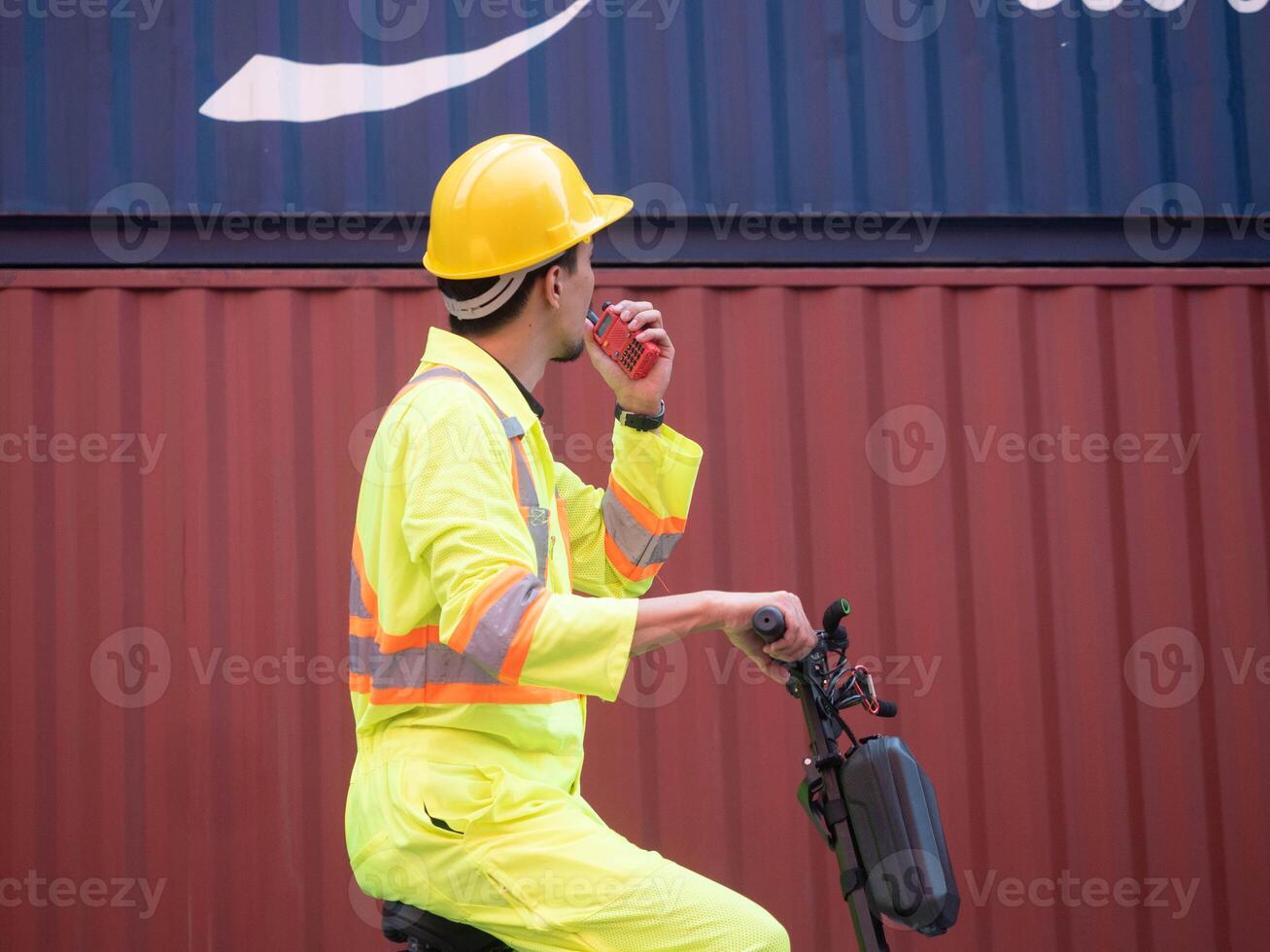 guidare scooterista uomo maschio auto auto parlando Radio talkie walkie giallo elmetto protettivo sicurezza indossare uniforme tecnico mezzi di trasporto opera lavoro contenitore importare esportare logistica carico contraente spedizione attività commerciale foto