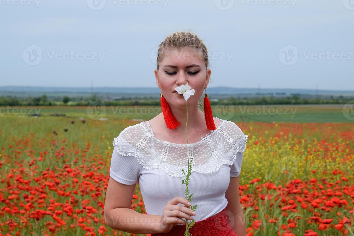 bianca papavero fiore nel il mani di un' ragazza nel il mezzo di un' campo di rosso papaveri foto