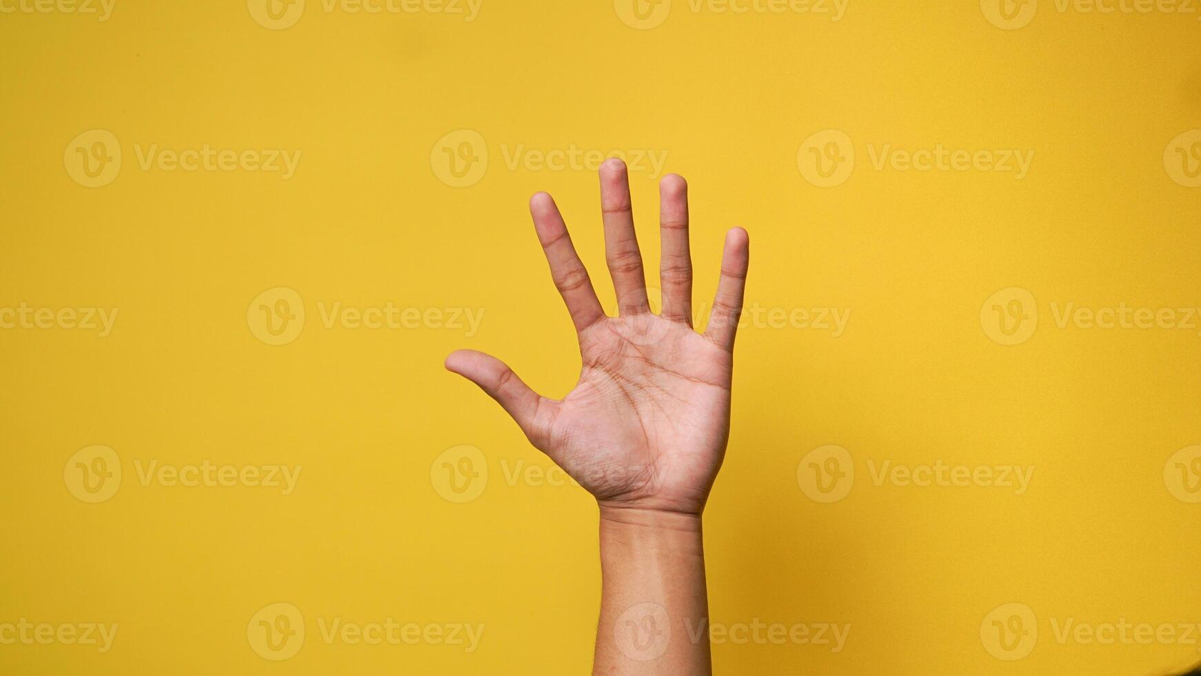 dell'uomo mano sollevamento su e agitando detto Ciao o chiede autorizzazione su un' giallo sfondo foto