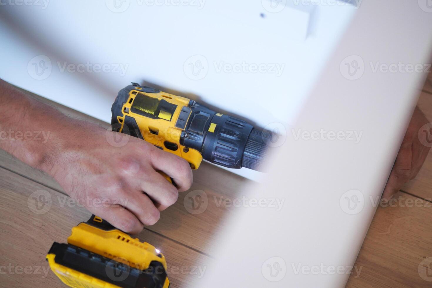 lento movimento di utilizzando elettrico perforazione su bianca di legno tavola foto