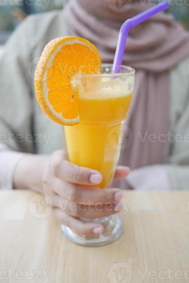 donne Tenere un' bicchiere di arancia succo foto