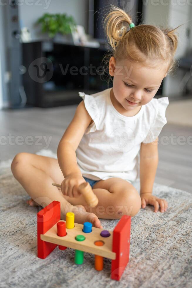 carino caucasico poco ragazza giocando su il pavimento a casa con eco di legno giocattoli. Montessori giocattolo. il bambino giocando educativo Giochi. foto