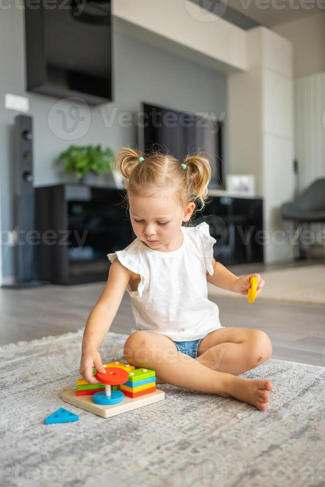 carino caucasico poco ragazza giocando su il pavimento a casa con eco di legno giocattoli. Montessori giocattolo. il bambino giocando educativo Giochi. foto