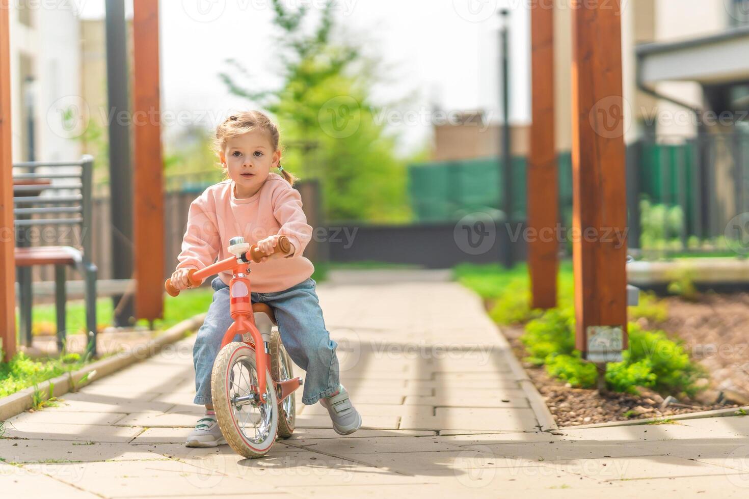 poco ragazza equitazione equilibrio bicicletta nel il cortile di il residenza nel praga, Europa foto