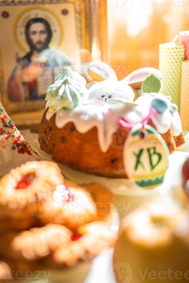 Pasqua torta con dipinto uova, mele e biscotti su tavolo nel casa cucina. Chiesa icone e candela su sfondo. ortodosso religione tema. alto qualità foto