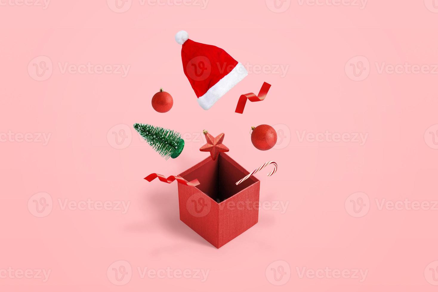confezione regalo aperta con decorazioni e cappello esce dal concetto di scatola. posizione isometrica. sfondo rosa pastello foto
