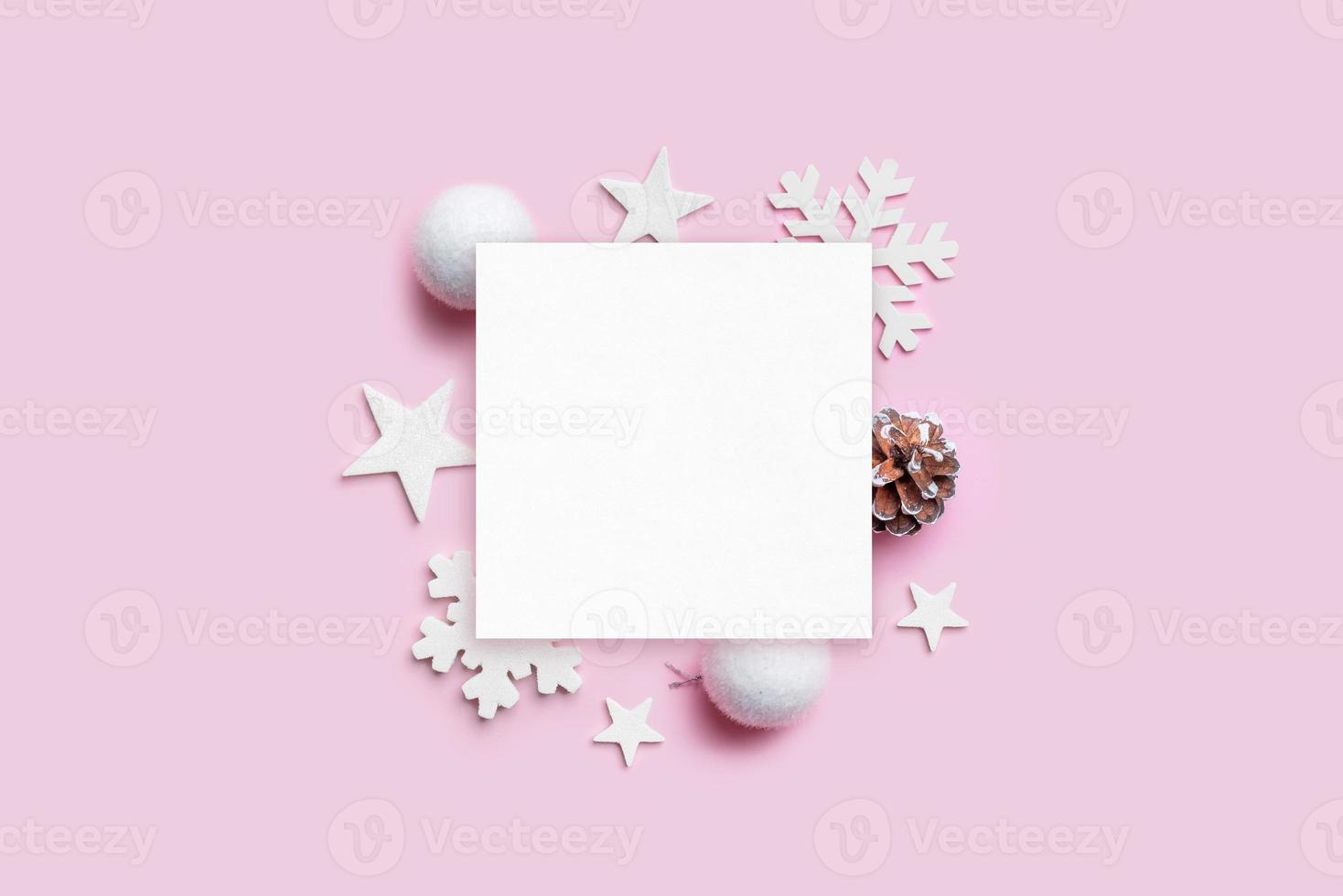 modello di biglietto di auguri di natale con decorazioni natalizie sulla scrivania rosa pastello. carta bianca per il testo di saluto. vista dall'alto, posizione piatta foto